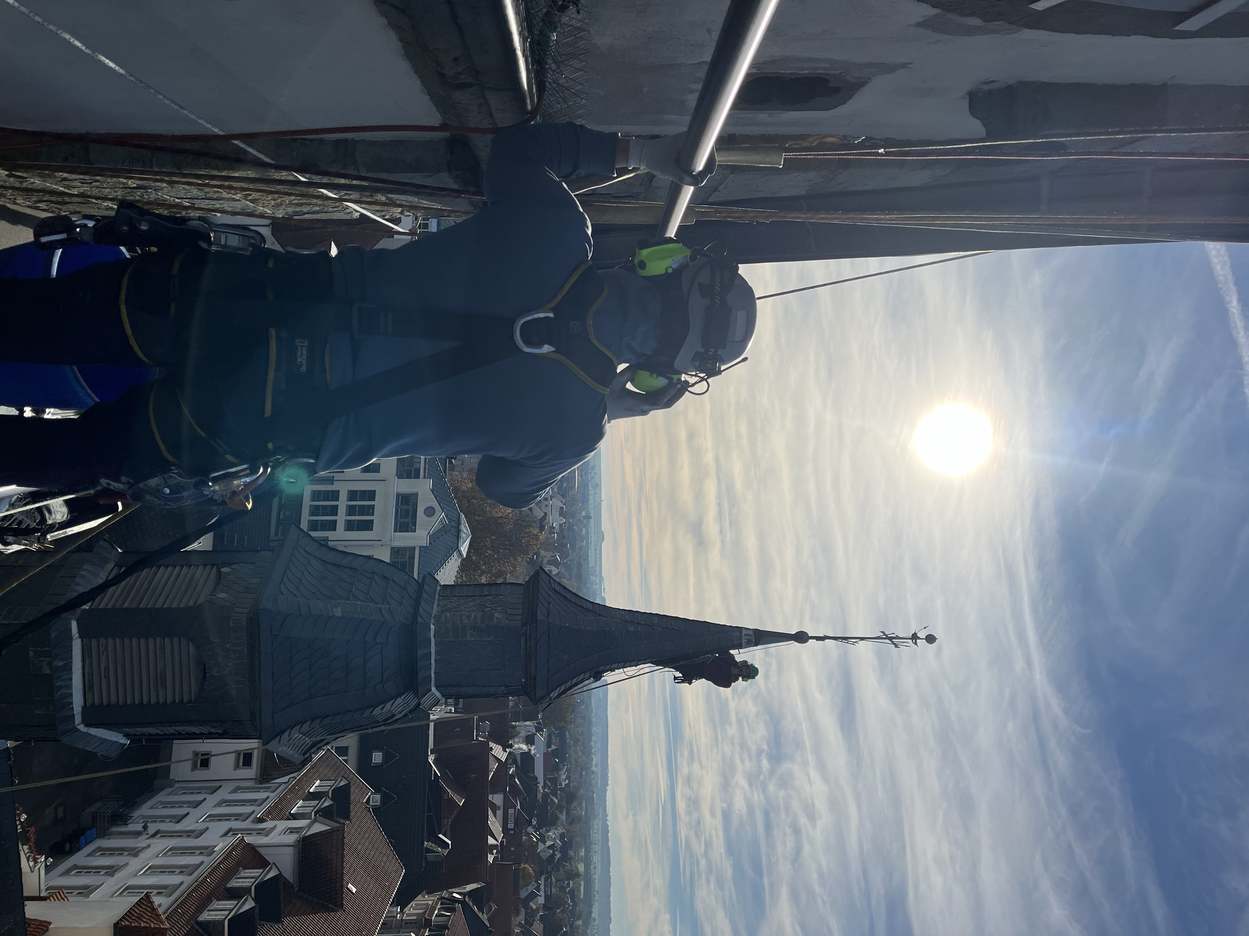 Industriekletterer am Kirchturm mit Stadtpanorama